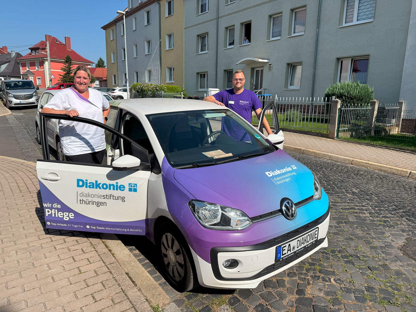 Mitarbeiterin und Mitarbeiter des Diakonie Pflegedienstes Eisenach stehen an ihrem Pflegedienstauto