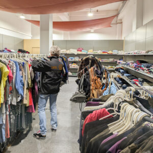 Frau hängt in der Tafel Bad Salzungen Kleidung auf Kleiderstangen