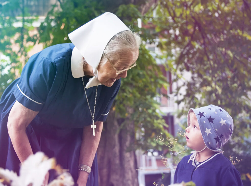 Diakonisse im Gespräch mit einem Kindergartenkind im Garten des Mutterhauses