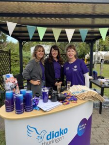 Diako-Mitarbeiterinnen am Infostand mit vielen Merch-Artikeln