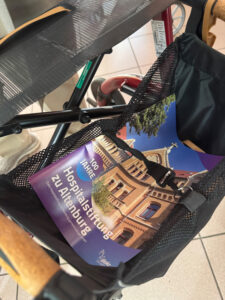 Nahaufnahme eines Rollators mit der Festschrift "100 Jahre Hospitalstiftung zu Altenburg" im Korb