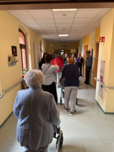 Führung durch das Haus, zu sehen ist ein Flur mit Seniorinnen und Senioren mit Rollatoren