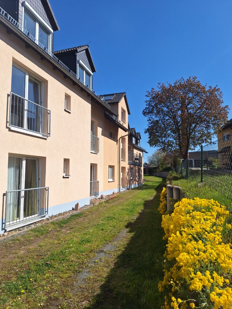 Besondere Wohnform Michaelishaus Schleiz, ein beige gestrichenes Haus im Grünen