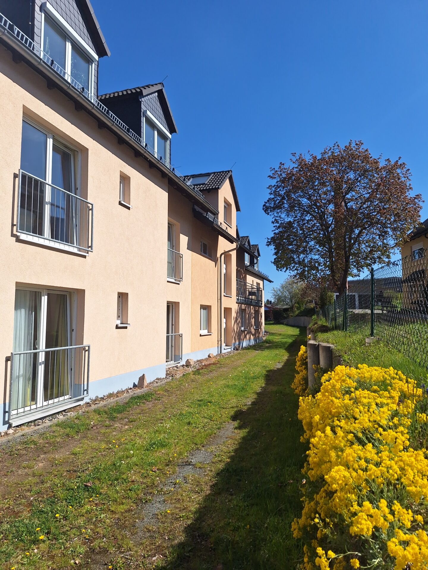 Besondere Wohnform Michaelishaus Schleiz, ein beige gestrichenes Haus im Grünen