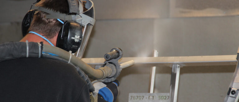 DeColor24 Salfeld - ein Mann bei Abschleifen von Metallgestellen