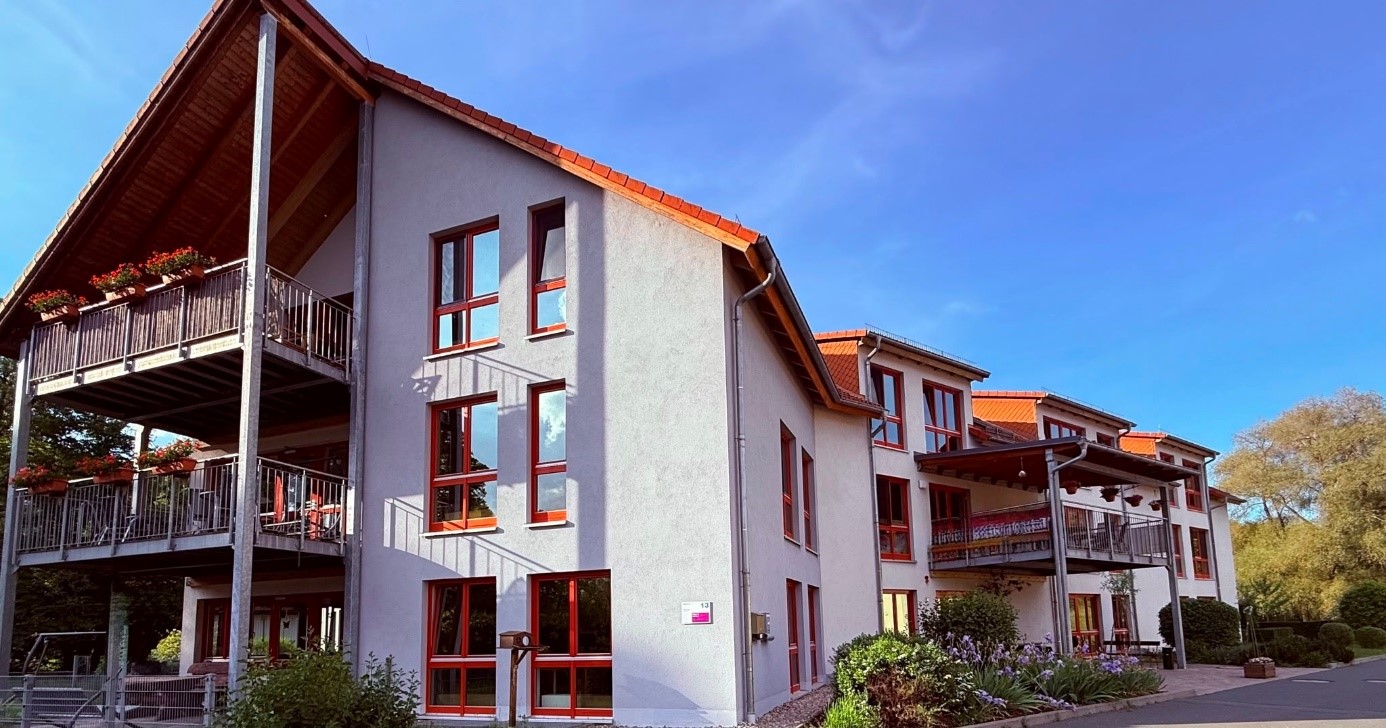 Johanneshof Quitteldorf_mehrgeschossiges Wohnhaus, weiße Fassade, rote Fenster