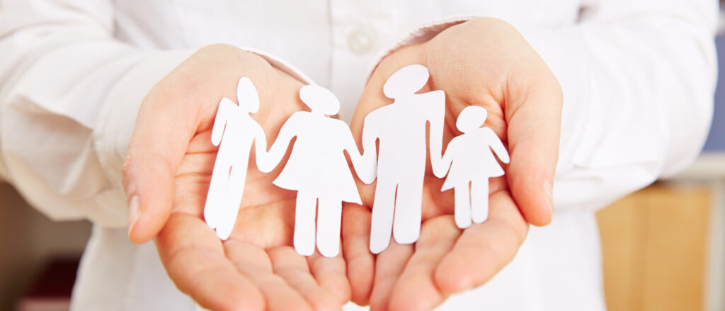 Familie aus Papier liegt sicher in den Händen einer Frau