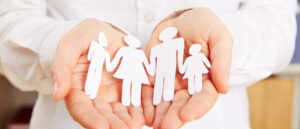 Familie aus Papier liegt sicher in den Händen einer Frau