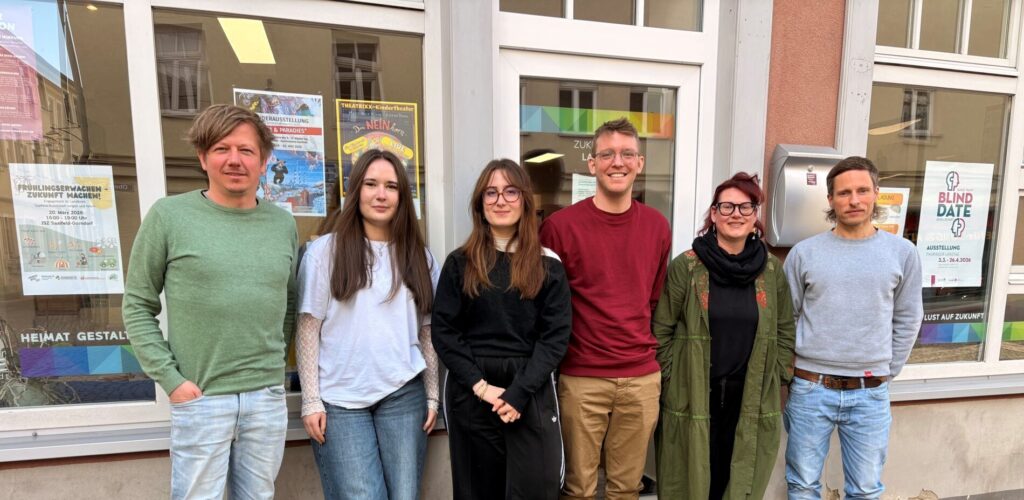 Team des Zukunftsladens in Saalfeld, sechs junge Menschen lehnen an einem Schaufenster