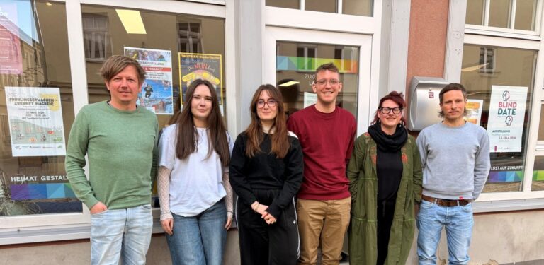 Team des Zukunftsladens in Saalfeld, sechs junge Menschen lehnen an einem Schaufenster