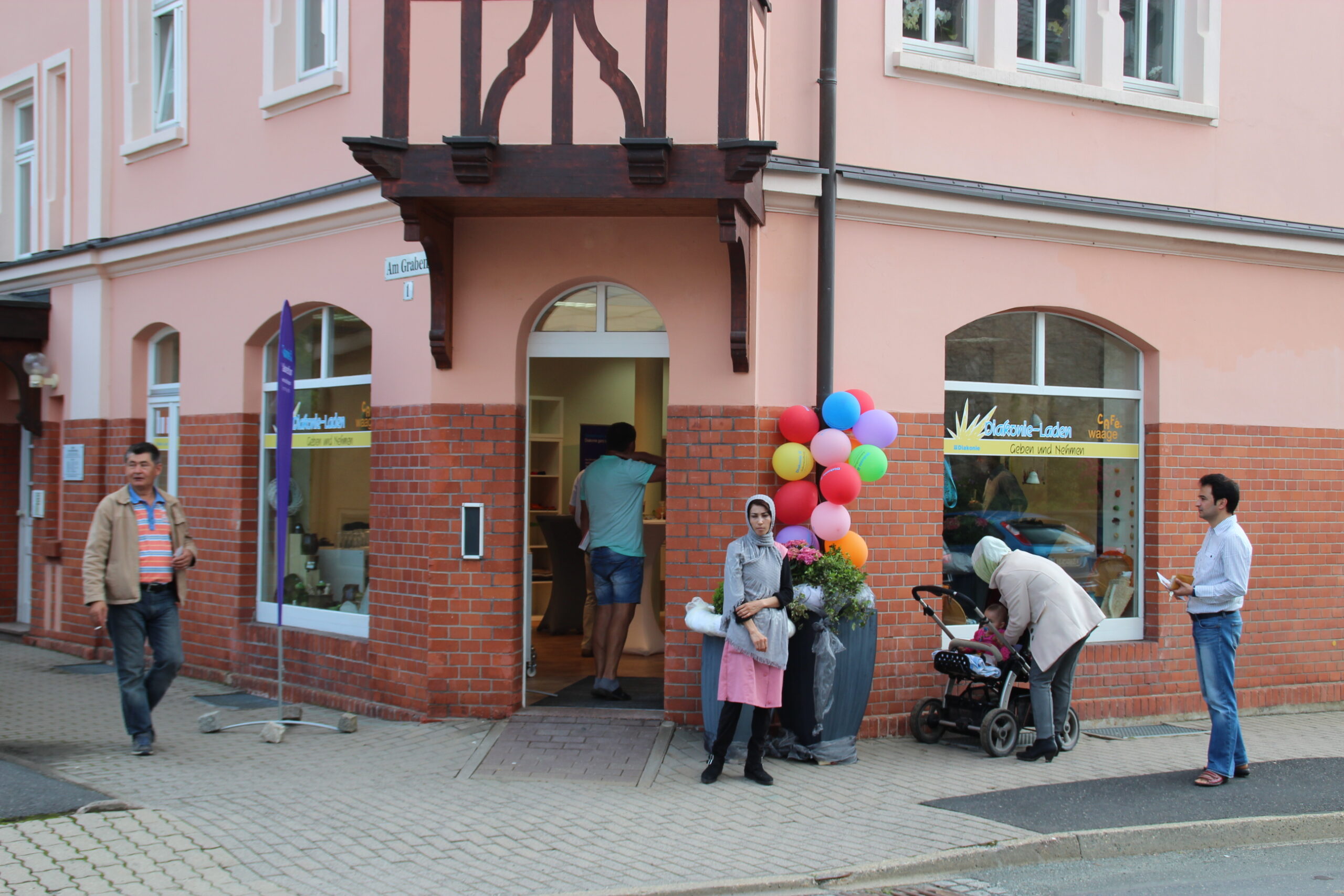 ThINKA Bad Lobenstein und Pößneck, Eingang zum Diakonieladen Bad Lobenstein mit Menschen und Luftballons