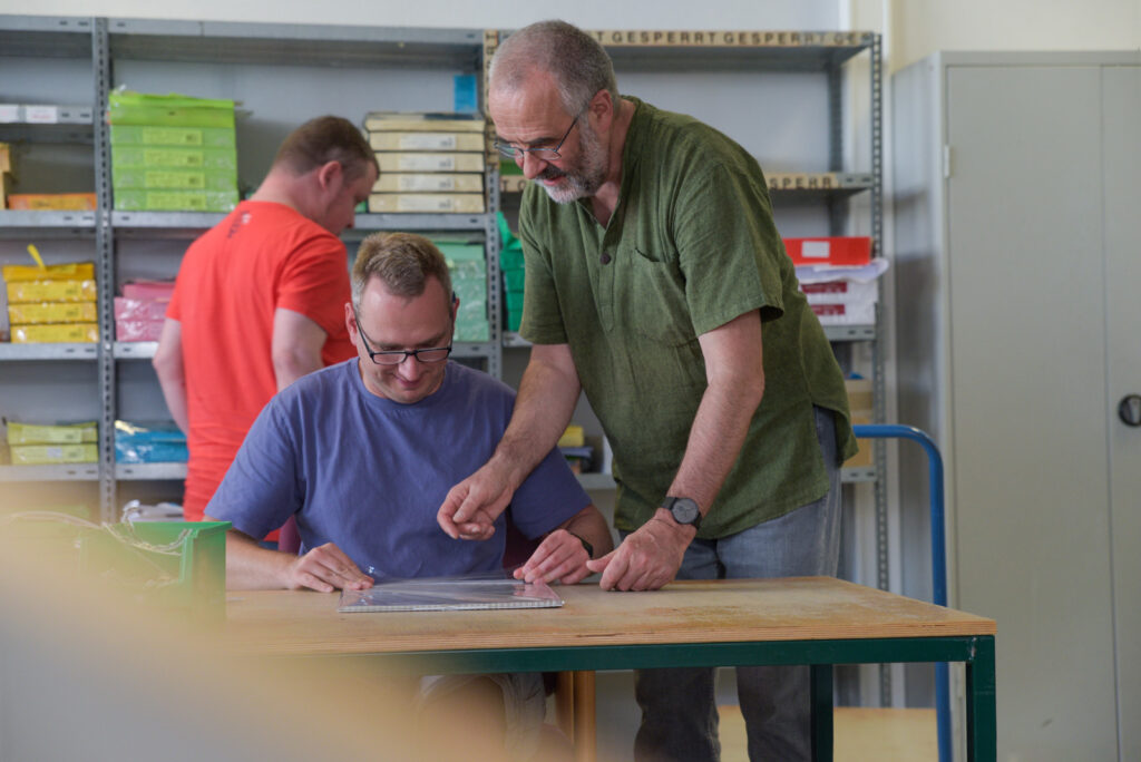 Drei Männer arbeiten gemeinsam an einem Schreibtisch bei Diakopie