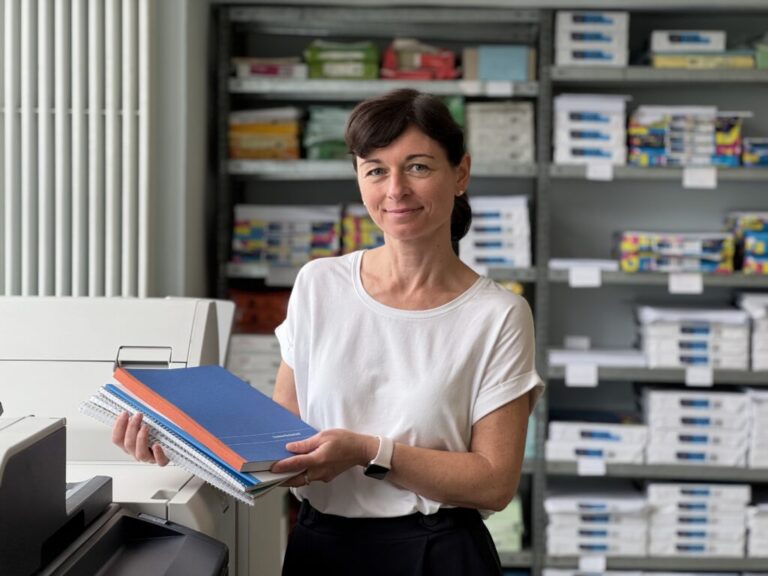 Eine Frau präsentiert verschiedene Druckerzeugnisse, die man bei Diakopie beauftragen kann