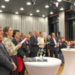 Gründungsfeier Diakoniestiftung Thüringen_012026 - viele Menschen stehen an Tischen, folgen einem Grußwort