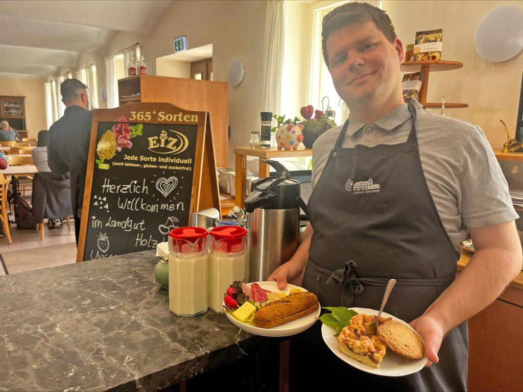 Cafeteria im Landgut Holzdorf_junger Mann trägt drei Teller