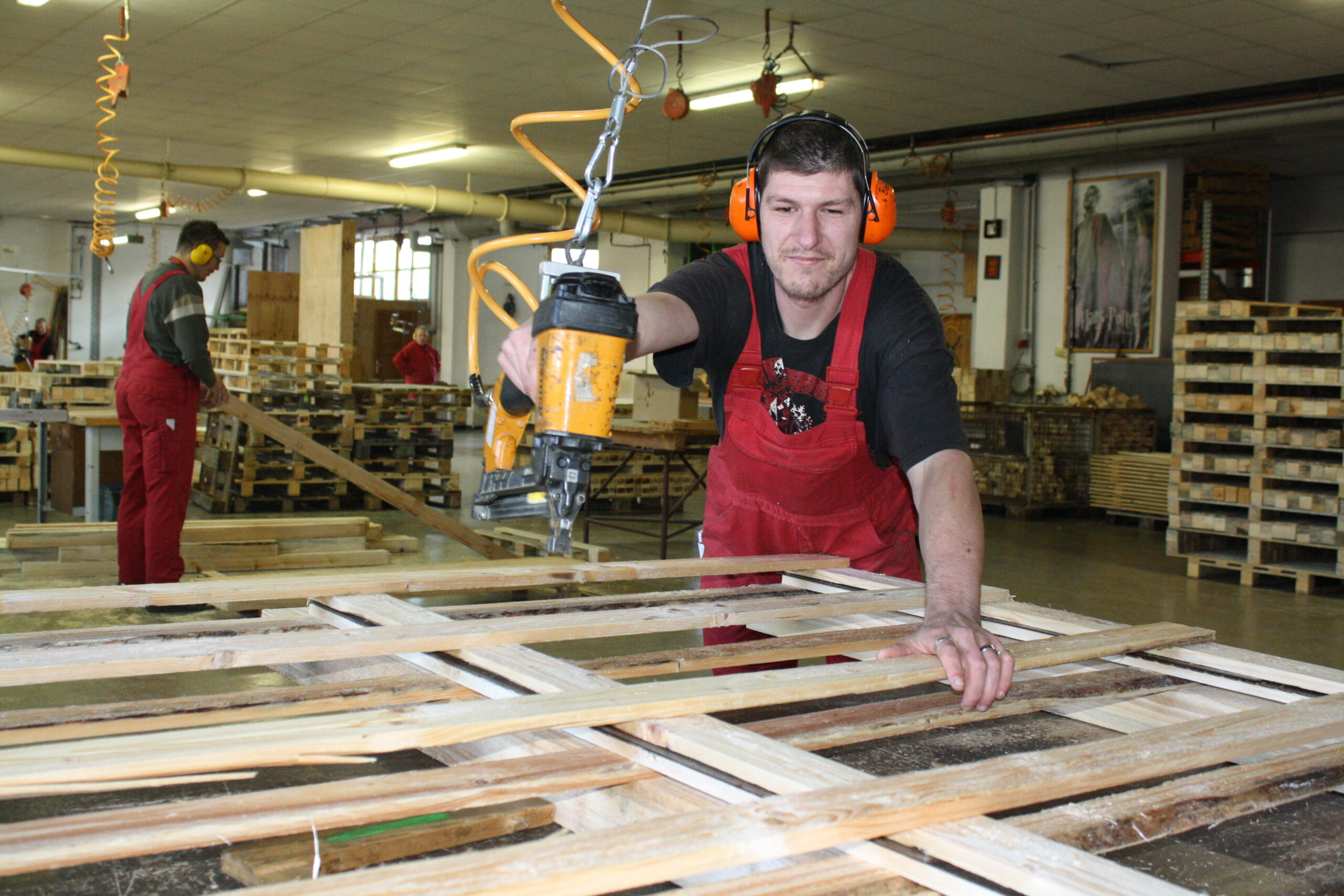 Holzwerkstatt-Werkstätten Christopherushof Altengesees_junger Mann schraubt eine Holzpalette zusammen