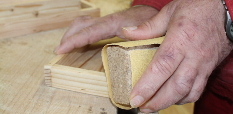 Holzwerkstatt-Werkstätten Christopherushof Altengesees_Hände schleifen ein Stück Holz mit Sandpapier