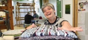 Weberei der Werkstätten Christopherushof in Altengesees, junge Frau mit gewebten Kissen