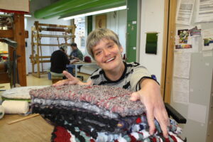 Weberei der Werkstätten Christopherushof in Altengesees, junge Frau mit gewebten Kissen