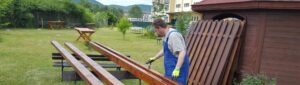 ein Mann streicht Bretter in einem Garten