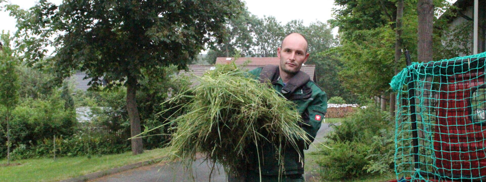 Saalfelder Werkstätten - ein Mann bei der Gartenarbeit, ein lädt Grünschnitt auf einen Anhänger