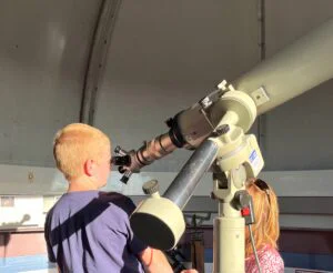 Kinder schauen in einer Sternwarte durch ein Fernrohr