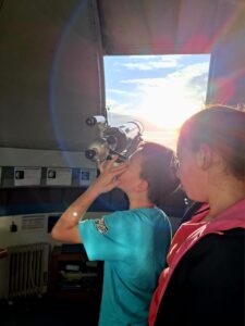 Kinder schauen in einer Sternwarte durch ein Fernrohr