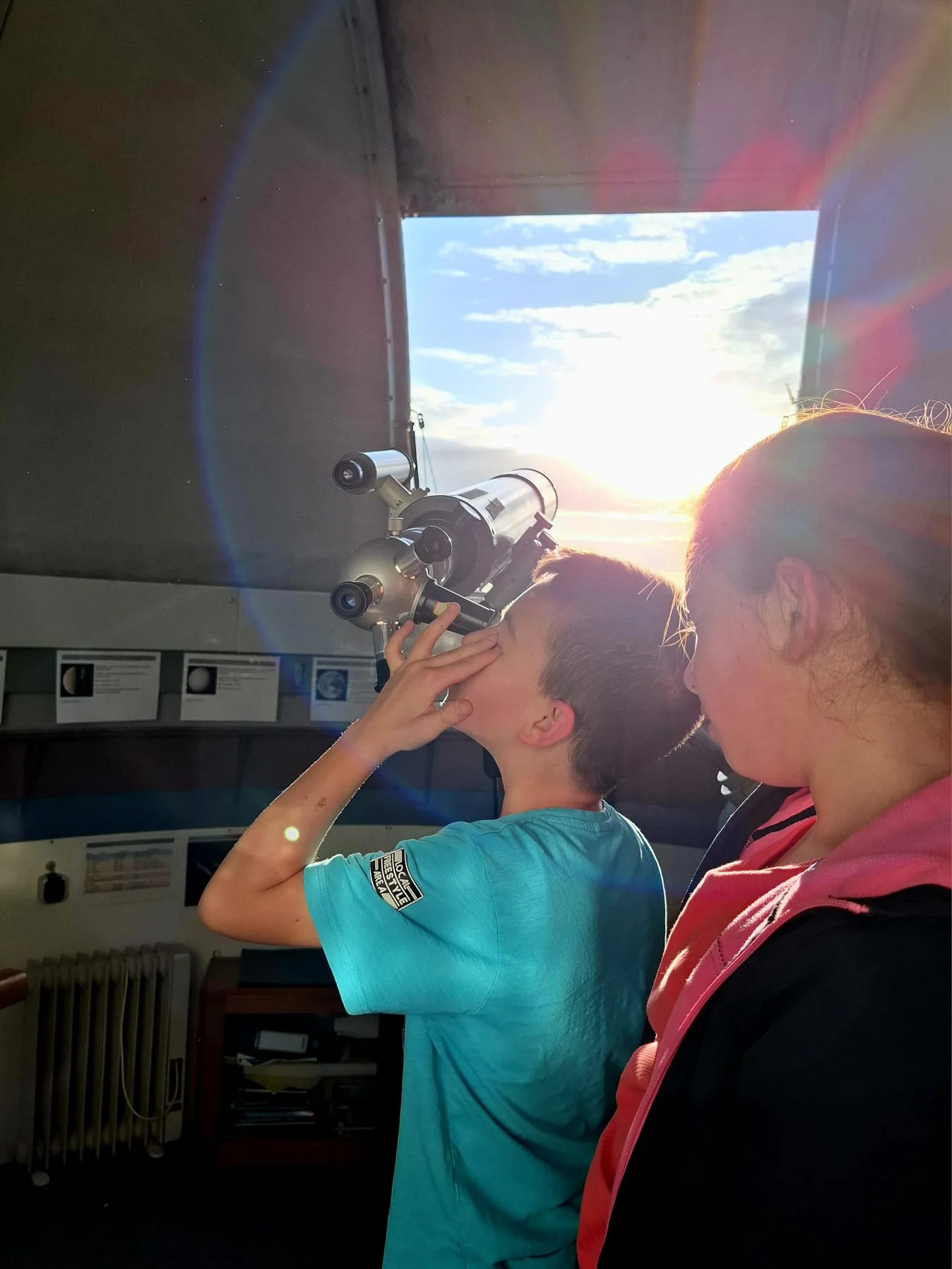 Kinder schauen in einer Sternwarte durch ein Fernrohr