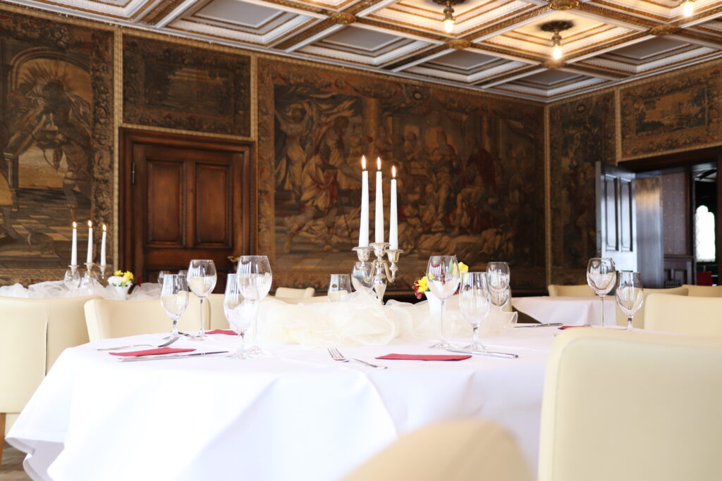 Landgut Holzdorf Blick in das Lederzimmer, festlich gedeckter Tisch mit großen Kerzenständer und brennenden Kerzen
