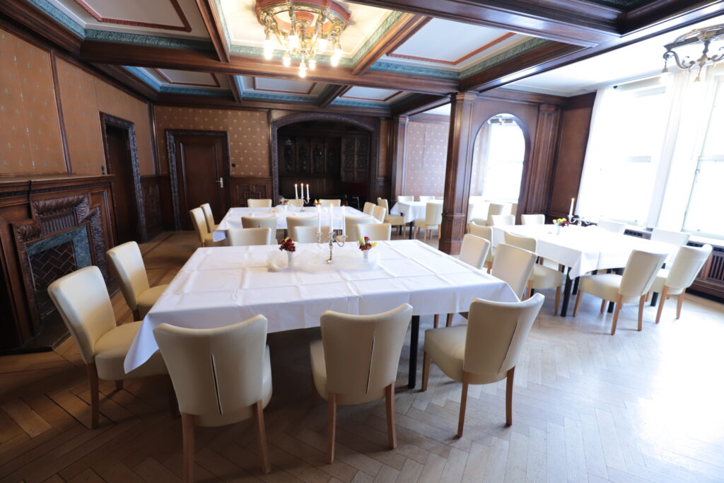 Landgut Holzdorf Blick in das Lederzimmer, Tafeln mit weißen Tischdecken und weißen Stühlen