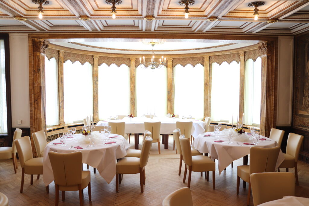 Landgut Holzdorf Blick in das Lederzimmer, Tafeln mit weißen Tischdecken und weißen Stühlen