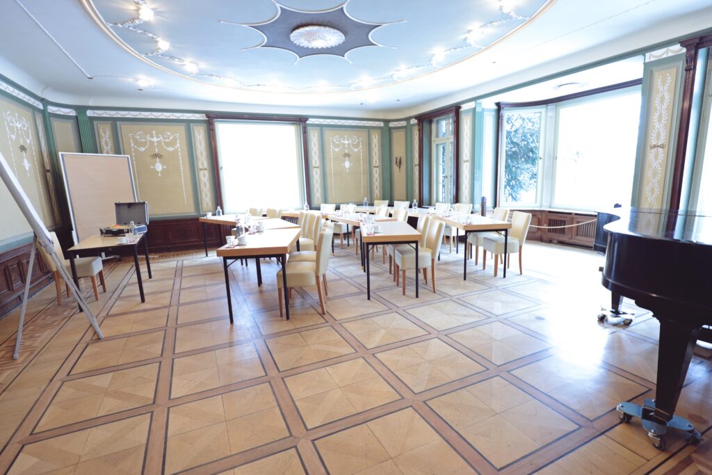 Landgut Holzdorf Blick in das Musikzimmer, weiße Stühle und Witheboard