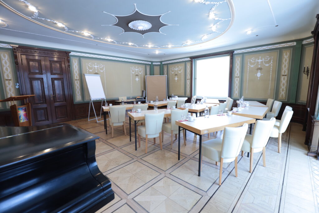 Landgut Holzdorf Blick in das Musikzimmer, weiße Stühle und Witheboard