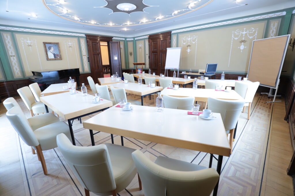 Landgut Holzdorf Blick in das Musikzimmer, weiße Stühle und Witheboard