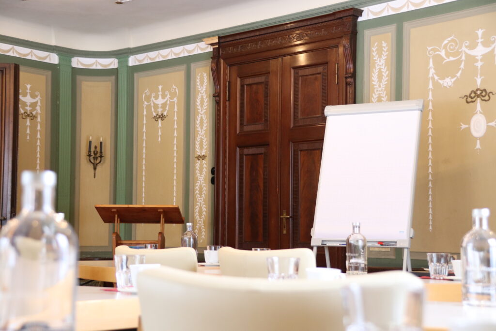 Landgut Holzdorf Blick in das Musikzimmer, weiße Stühle und Witheboard