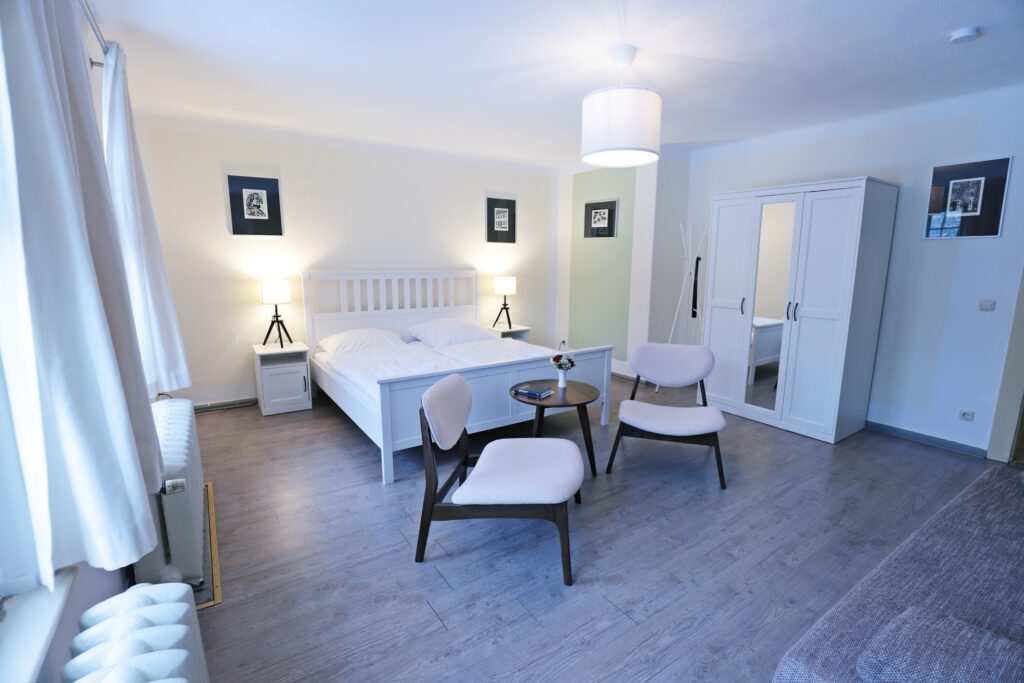 Landgut Holzdorf Blick in ein Pensionszimmer mit Bett und zwei Stühlen