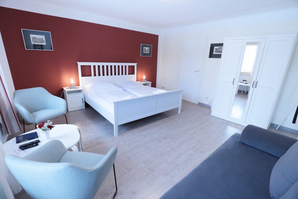 Landgut Holzdorf Blick in ein Pensionszimmer mit Bett und zwei Stühlen