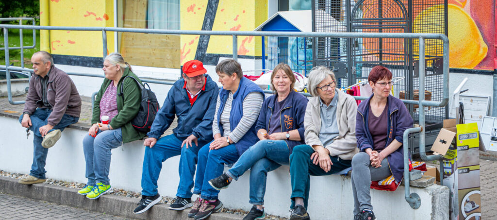 Tafel Blankenhain-acht Helfer sitzen auf einer Mauer vor dem Gebäude