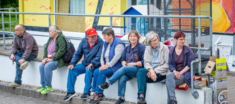 Tafel Blankenhain-acht Helfer sitzen auf einer Mauer vor dem Gebäude