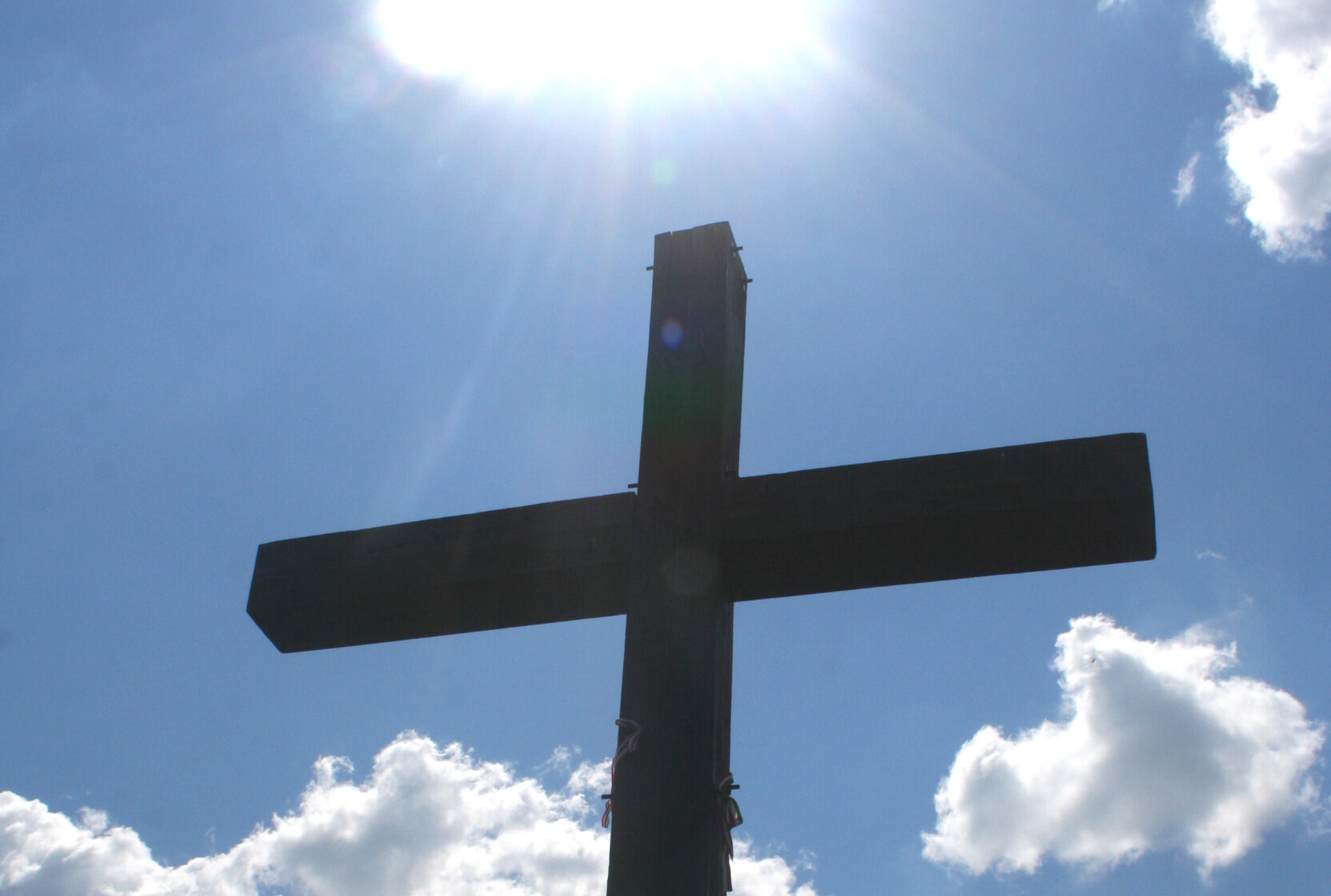 Großes Holzkreuz von unten nach oben fotografiert, Blick zum Himmel in die Sonne
