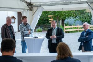 Inbetriebnahme der PV-Anlage auf dem Dach der Eisenacher Werkstätten - vier Männer an Stehtischen, Grüßworte