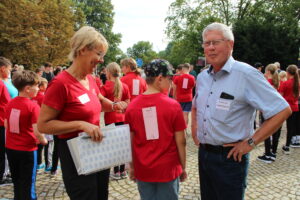 Spendenlauf der Michaelisschule Bad Lobenstein - zwei Erwachsene mit einem Schüler, er hat auf dem Rücken einen Stempelzettel zum Runden zählen 