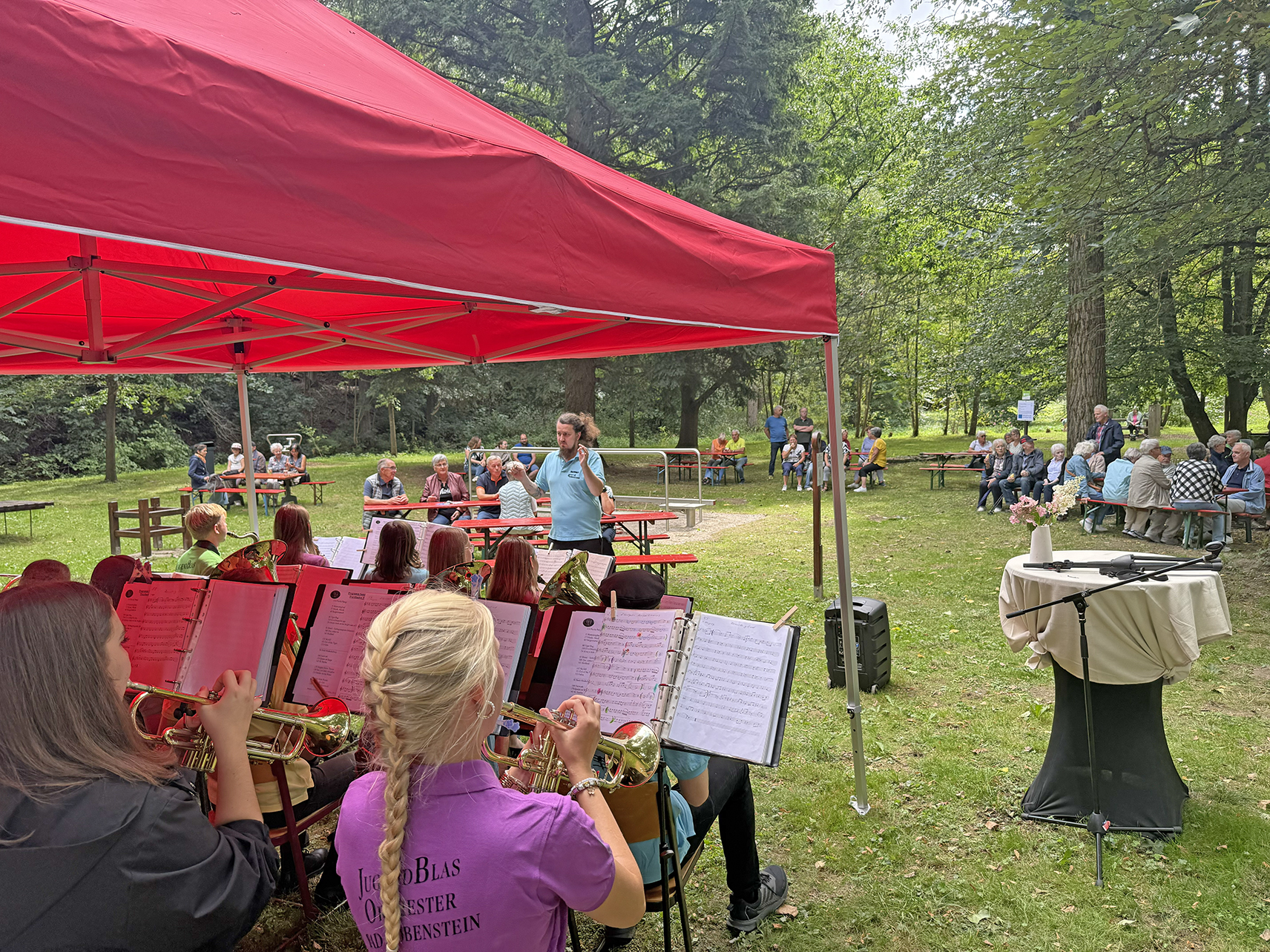Sommerkonzrt des ambulanten Hospizdienstes im Saale-Orla-Kreis, Blick auf Musikanten mit Dirigent im Park