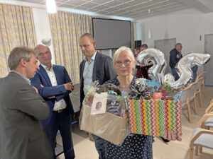 35 Jahre Kindergarten im Haus Gottesschutz - Festgottesdienst eine Frau hält Geschenke mit großer 35, drei Männer reden im Hintergrund