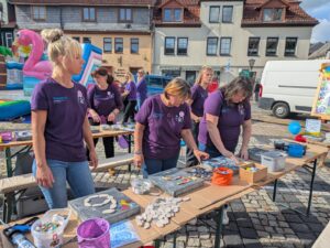 Tag der Diakonie in Bad Blankenburg - drei Frauen im lila Shirt mit Kreativangeboten an Bierzelttischen 